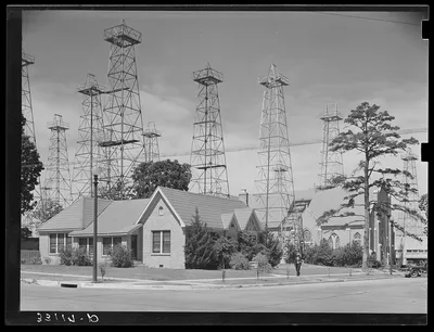 Derricks in residential section of Kilgore, Texas. Notice church, 1939