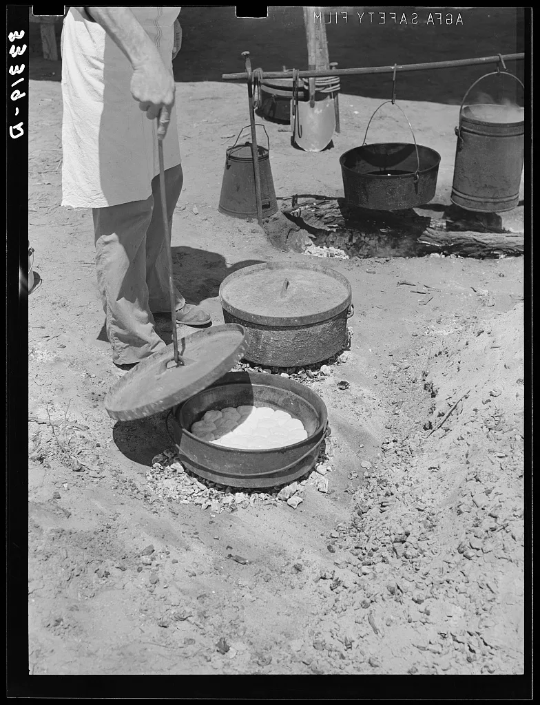 Cook of SMS Ranch making bread in Dutch oven. Near Spur, Texas, 1939