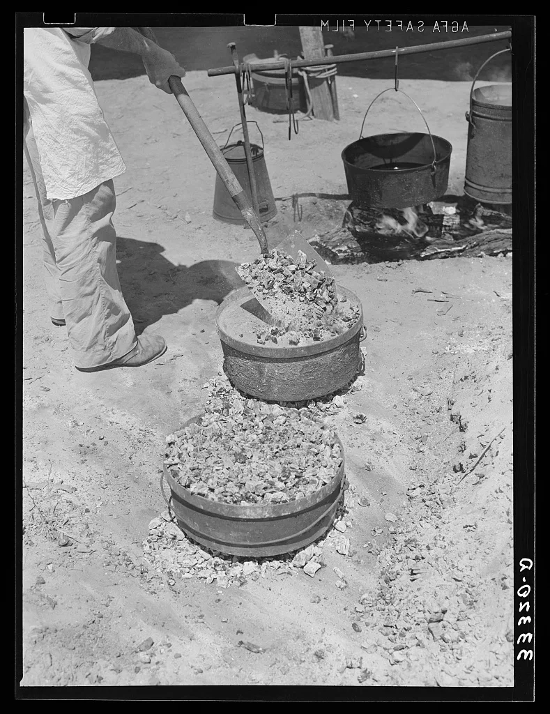 Piling coals on top of Dutch oven to bake bread. Ranch near Spur,…, 1939