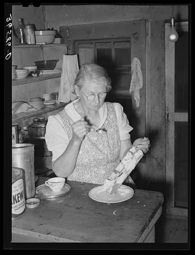 Mrs. Holley Sr. eating ice cream from the dasher. Pie Town, New Mexico, 1940