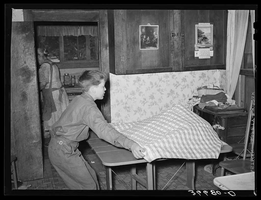 The Huttons' grandson putting on the table cloth. Pie Town, New Mexico, 1940
