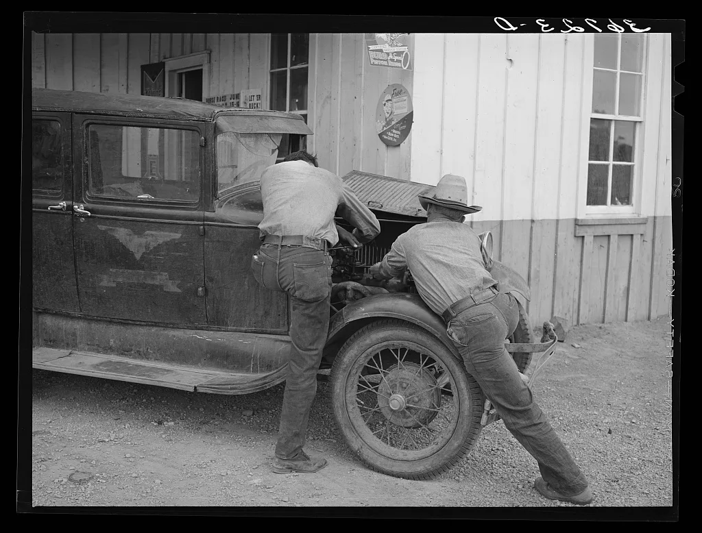 Garage owner and farmer working on a car. Pie Town, New Mexico. The…, 1940