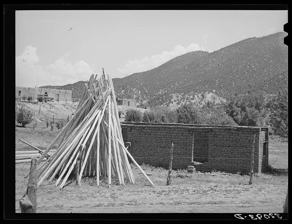 Poles used for vigas (roof construction) and adobe house under…, New Mexico, 1940