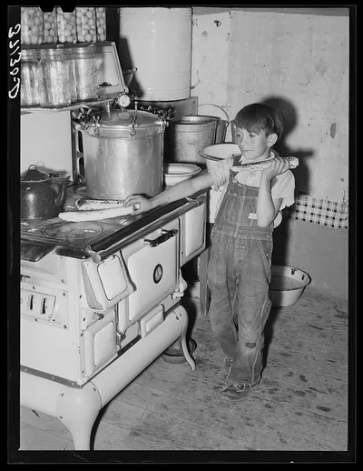 Spanish-American boy eating sweet corn which he has roasted on top of…, New Mexico, 1940