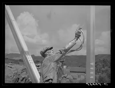 Workmen spraying a bridge with silver paint. Sapinero, Colorado, 1940