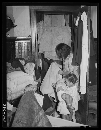Corner of bedroom with Negro housewife examining bed clothing chewed…, Illinois, 1941