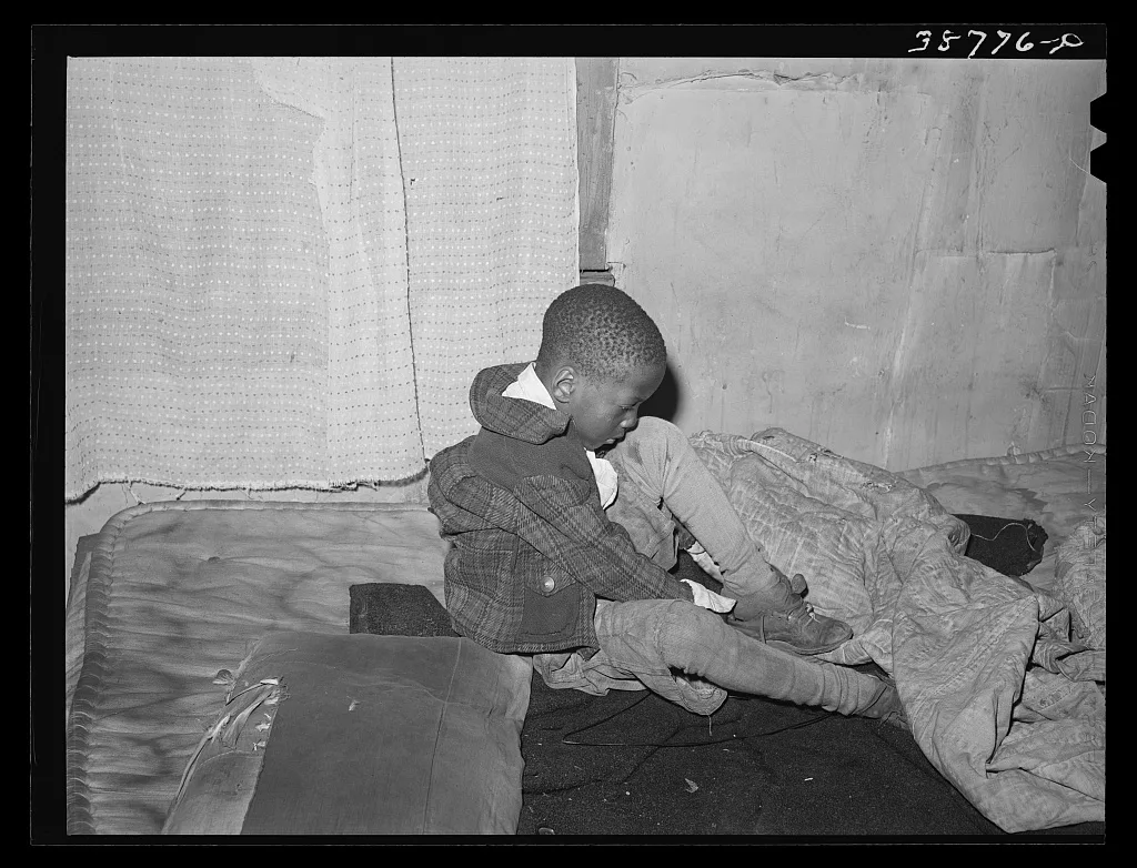 Little boy putting on his shoes. Chicago, Illinois, 1941